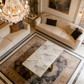 Luxurious living room with beige sofas, marble coffee table, and chandelier.