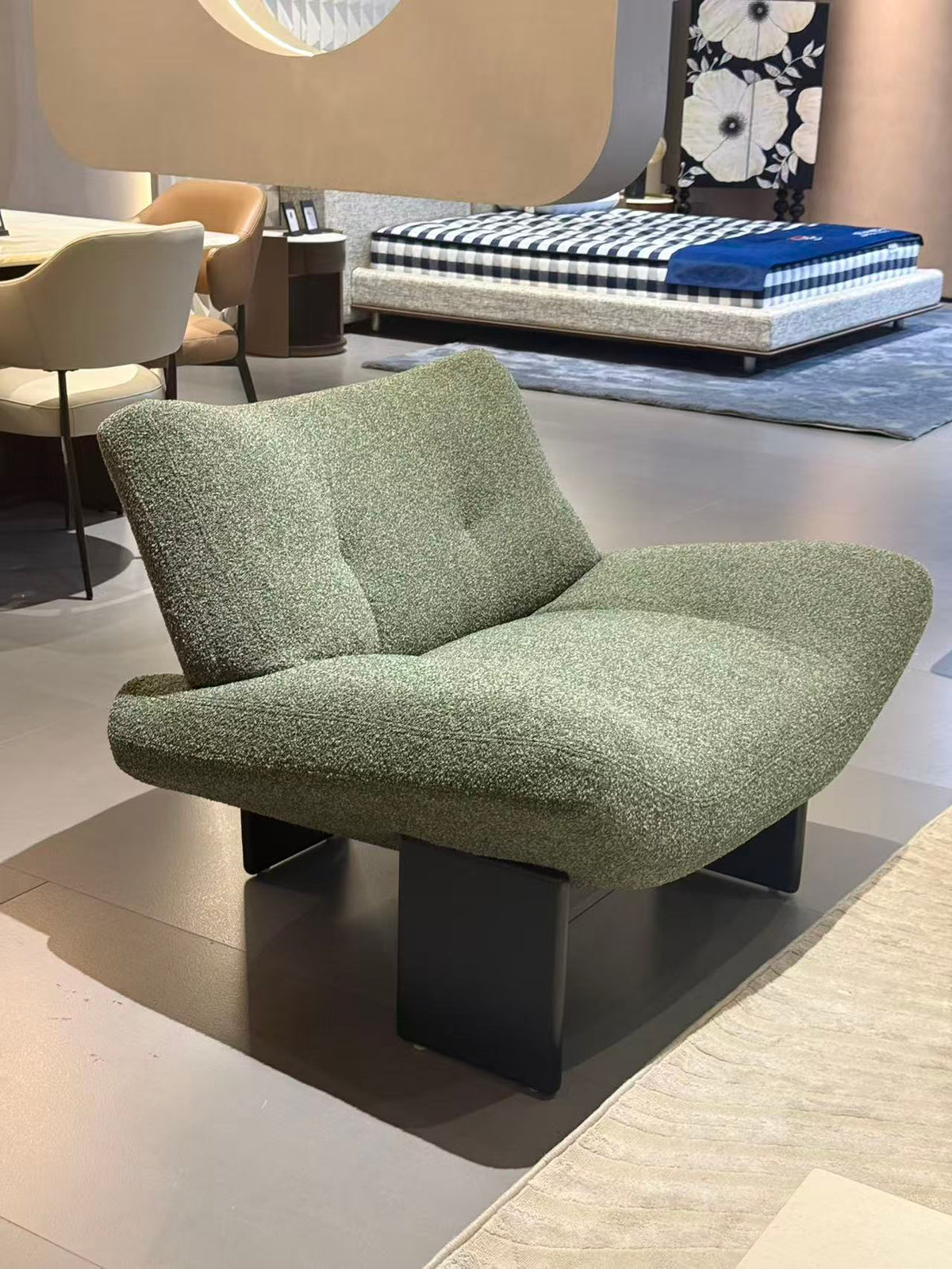 NORA green textured lounge chair with a curved seat and black geometric base.